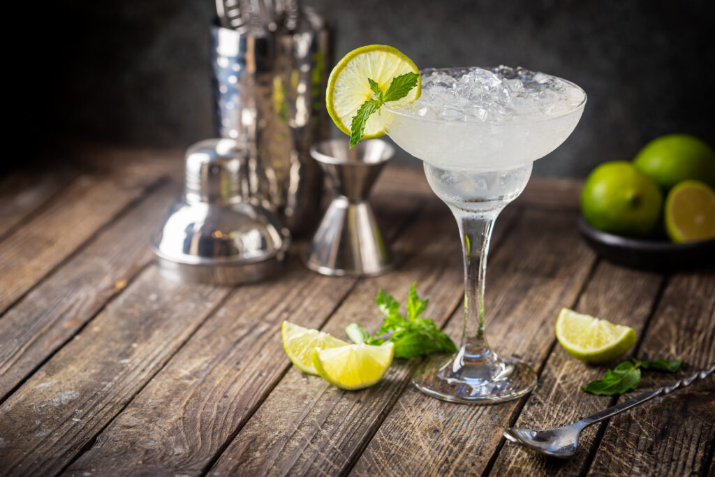 Cocktail margarita garnished with lime and mint on wooden background